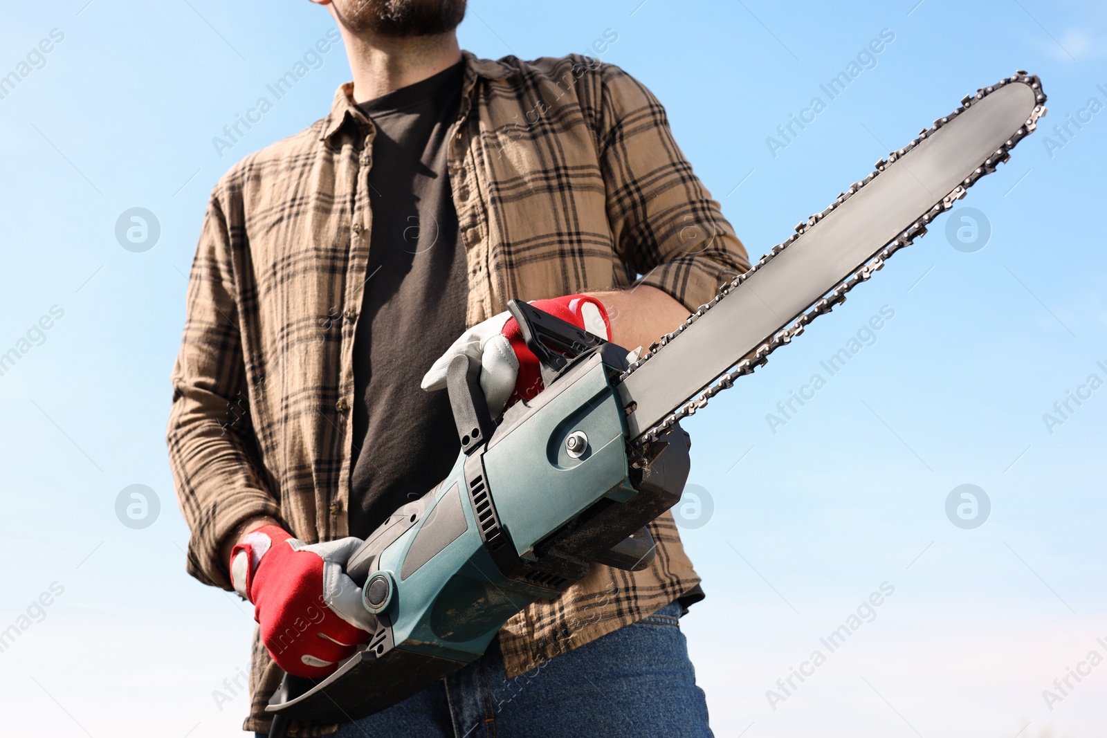 Photo of Man with modern saw against blue sky, closeup