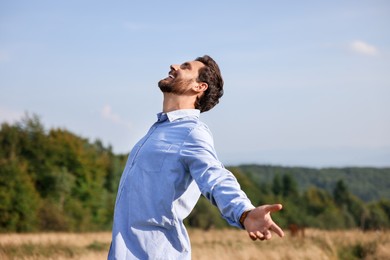 Photo of Feeling freedom. Happy man with wide open arms on meadow