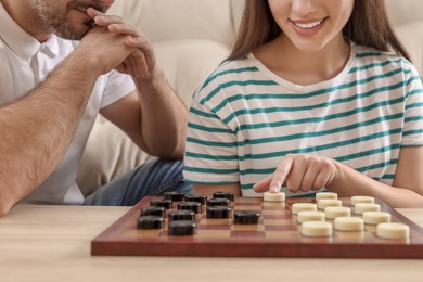 Photo of Couple playing checkers at table in room, closeup