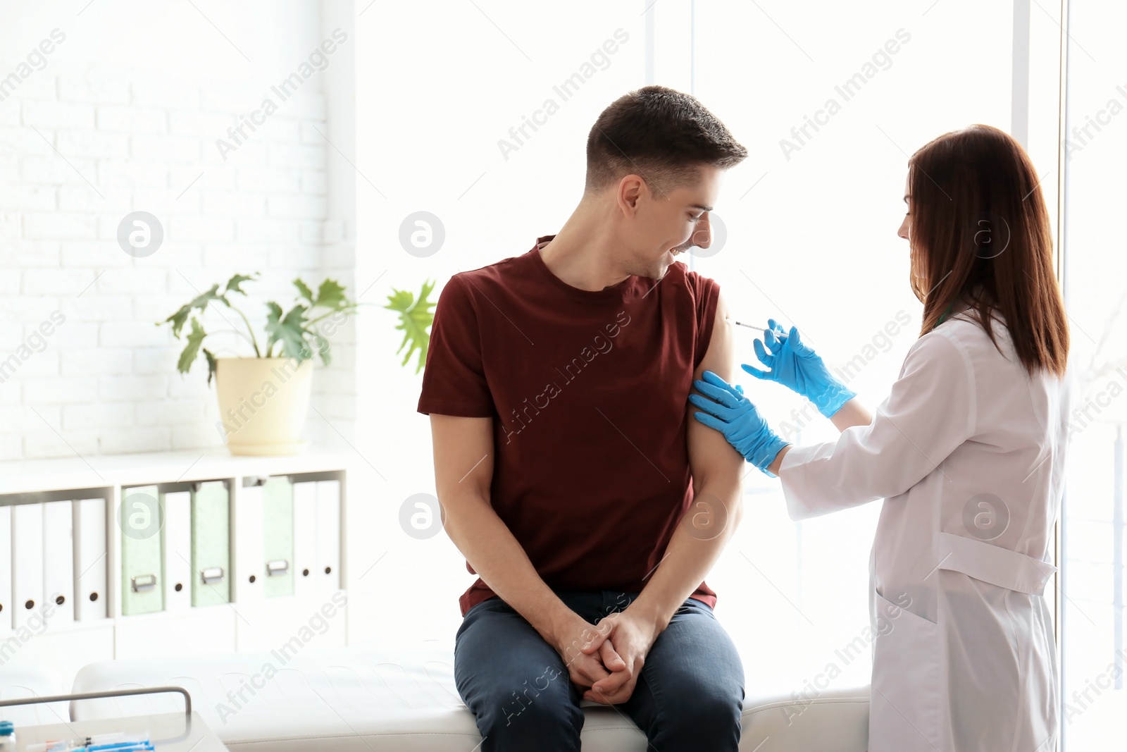 Photo of Doctor vaccinating male patient in clinic