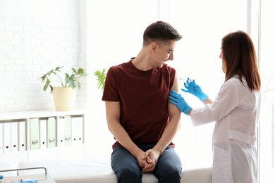 Doctor vaccinating male patient in clinic