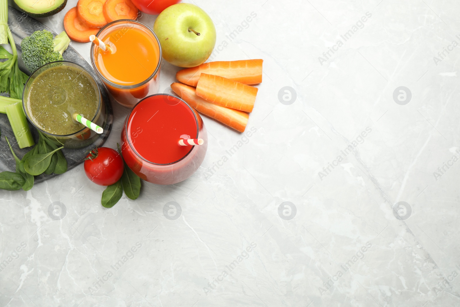 Photo of Delicious vegetable juices and fresh ingredients on light grey table, flat lay. Space for text
