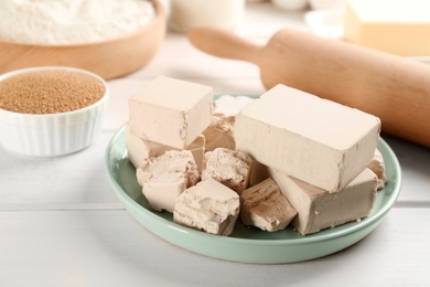 Compressed and granulated yeast on white wooden table