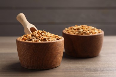 Photo of Bowls of dried orange zest seasoning on wooden table