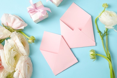 Photo of Flat lay composition with beautiful ranunculus flowers and envelopes on color background