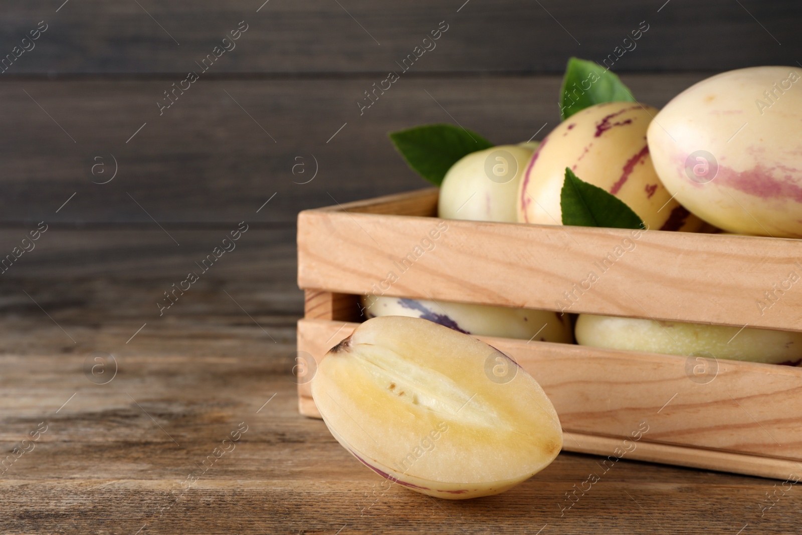 Photo of Fresh ripe pepino melons on wooden table, space for text