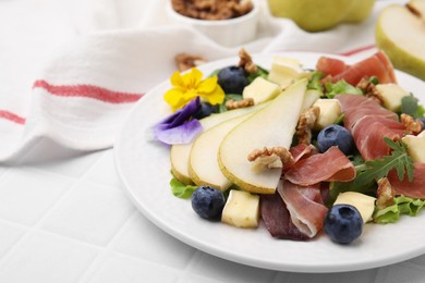 Photo of Tasty salad with brie cheese, prosciutto, walnuts and pear on white tiled table, closeup. Space for text
