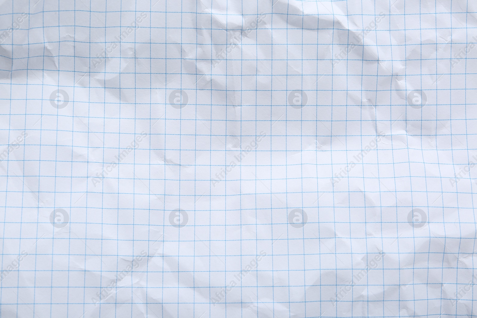 Photo of Crumpled checkered notebook sheet as background, top view
