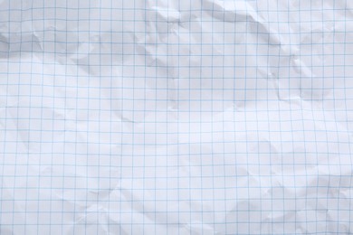 Photo of Crumpled checkered notebook sheet as background, top view