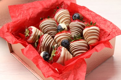 Box with delicious chocolate covered strawberries and blueberries on white table