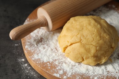 Photo of Making shortcrust pastry. Raw dough, flour and rolling pin on grey table