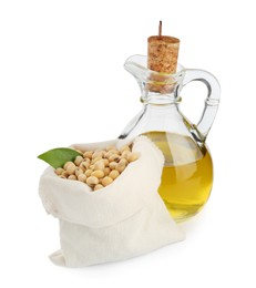 Photo of Glass jug of oil and soybeans on white background