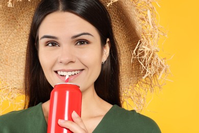 Photo of Beautiful happy woman drinking from red beverage can on yellow background, closeup