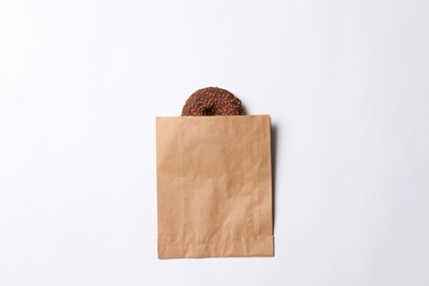 Photo of Paper bag with chocolate doughnut on white background, top view. Space for design