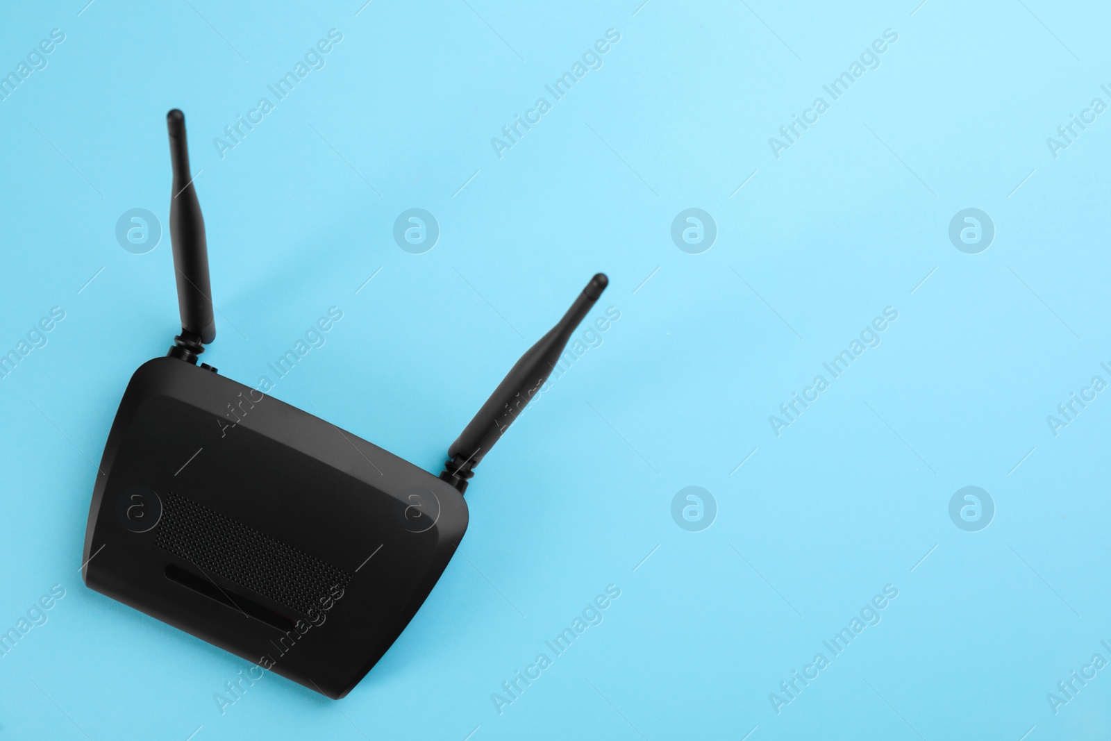 Photo of Modern Wi-Fi router on light blue background, top view. Space for text