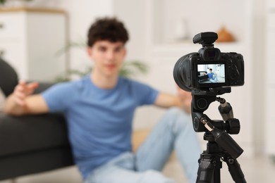 Photo of Teenage blogger explaining something while streaming at home, focus on camera