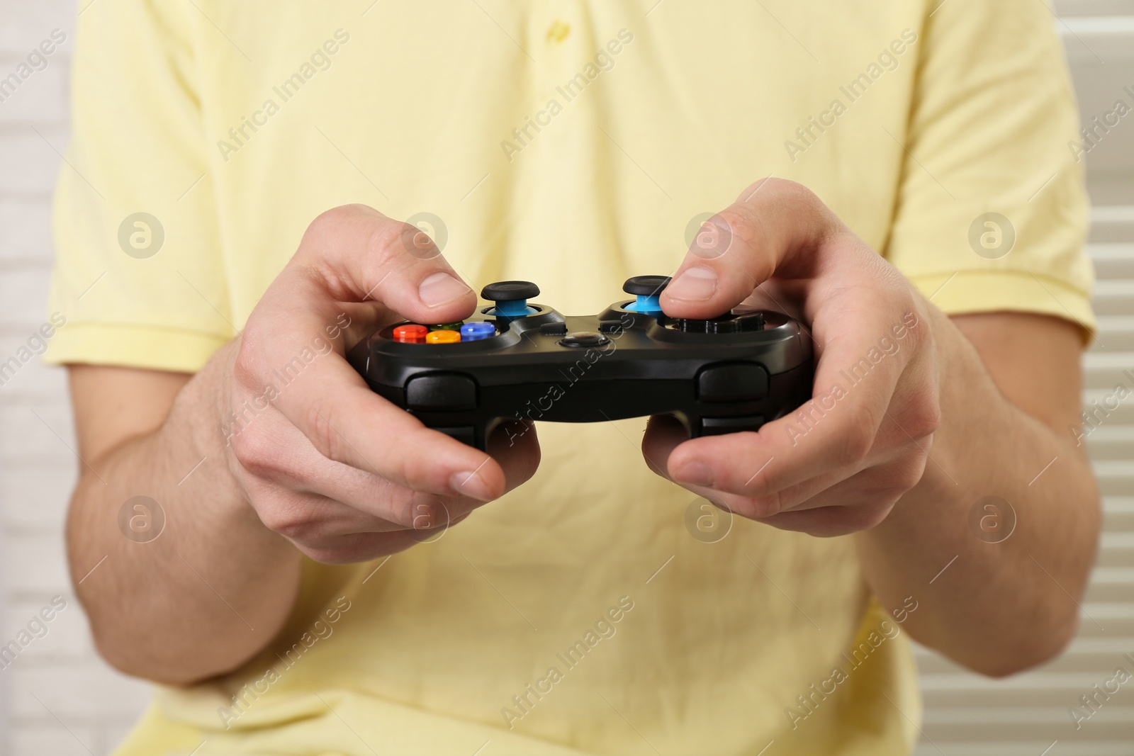 Photo of Man using wireless game controller indoors, closeup