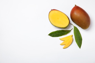 Tropical cut and whole mango with green leaves isolated on white, flat lay. Space for text