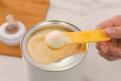 Photo of Woman with powdered infant formula at table, closeup. Preparing baby milk