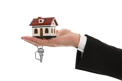 Photo of Real estate agent holding house model and key on white background, closeup