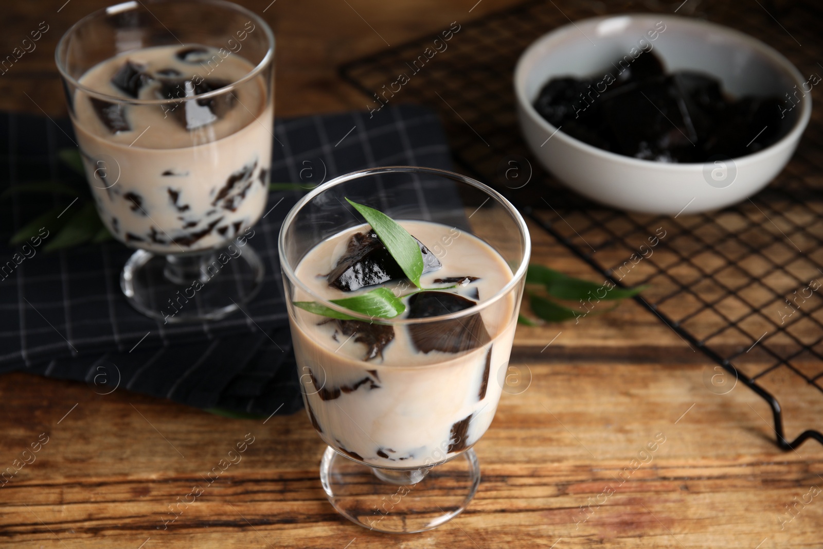 Photo of Glass of milk with grass jelly and green leaf on wooden table