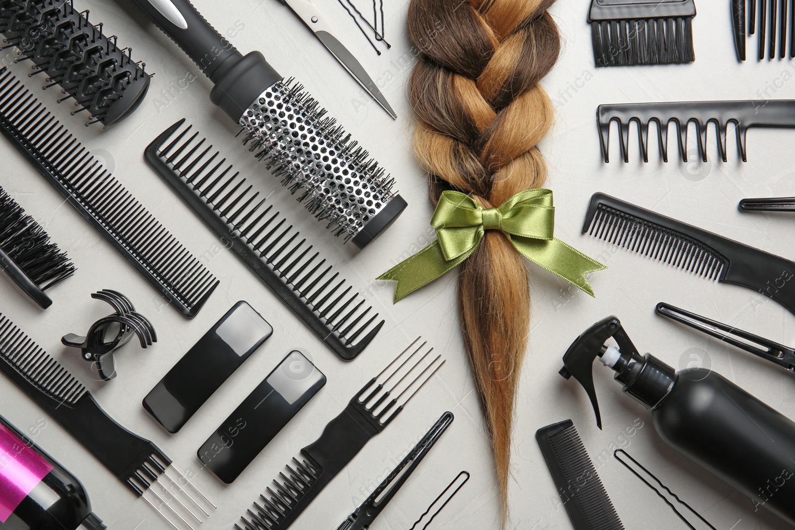 Photo of Flat lay composition with braid and hairdresser's tools on gray background