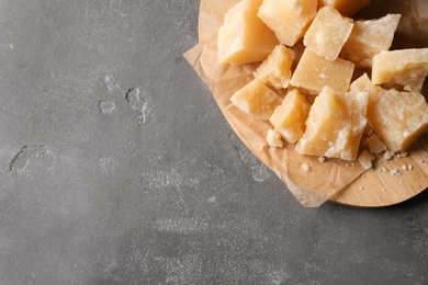 Pieces of delicious parmesan cheese on grey table, top view. Space for text