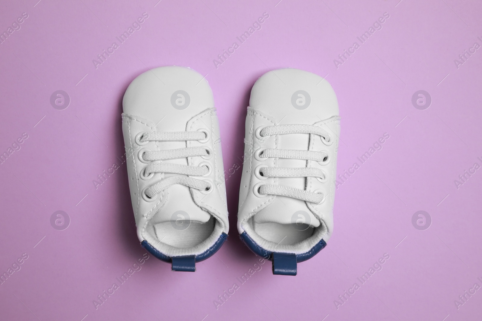 Photo of Cute baby shoes on violet background, flat lay