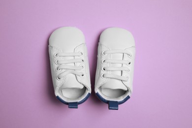 Cute baby shoes on violet background, flat lay