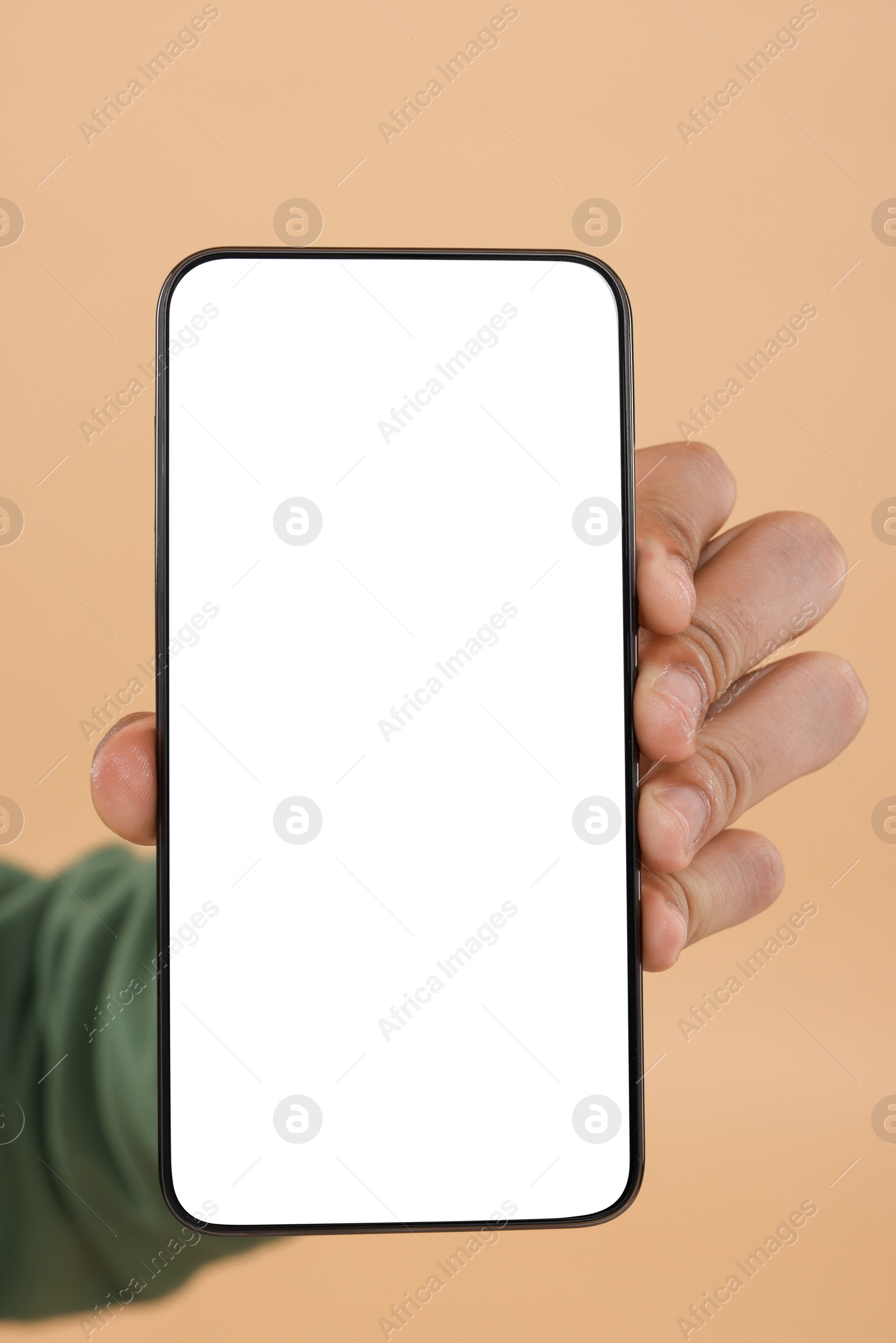 Photo of Man holding smartphone with blank screen on beige background, closeup