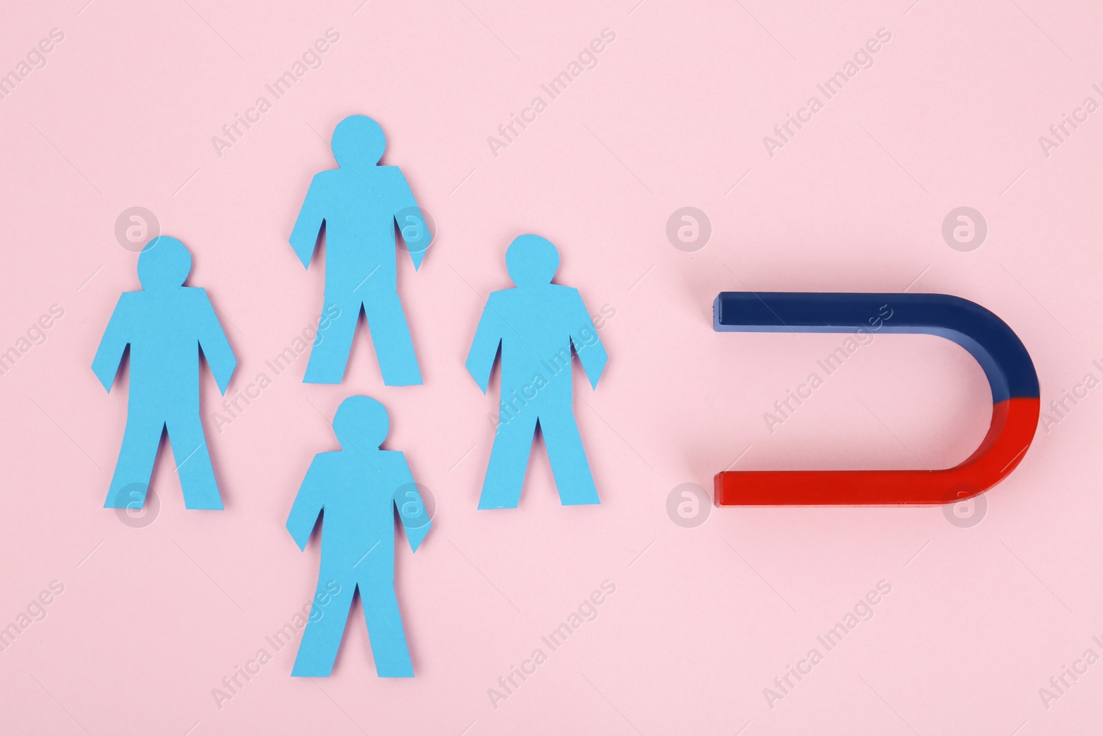 Photo of Magnet attracting paper people on pink background, flat lay
