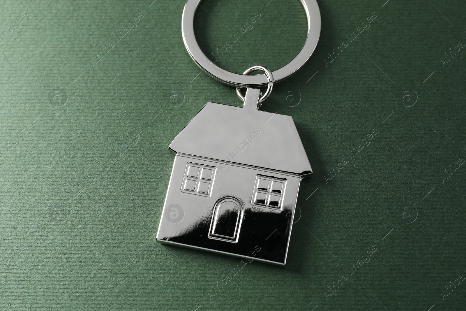 Photo of Metallic keychain in shape of house on dark green background, above view