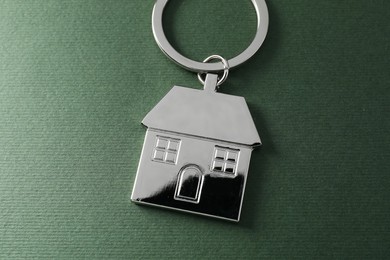 Metallic keychain in shape of house on dark green background, above view