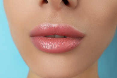 Photo of Woman with beautiful full lips on light blue background, closeup
