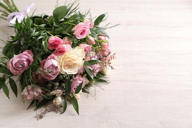 Photo of Beautiful bouquet with roses on light wooden table. Space for text