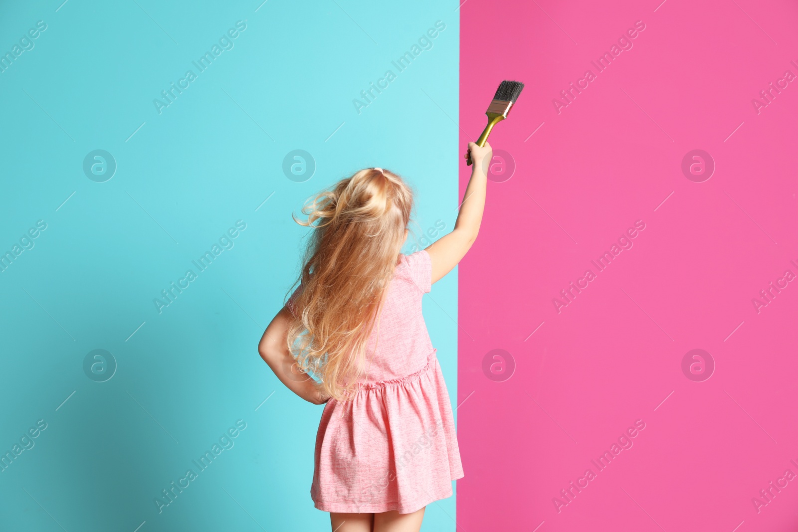 Photo of Little child painting color wall with brush