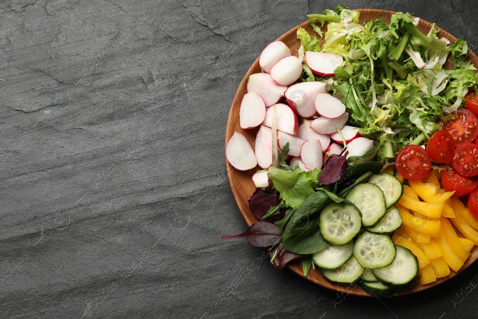 Photo of Vegetarian diet. Plate with tasty vegetables on black table, top view. Space for text