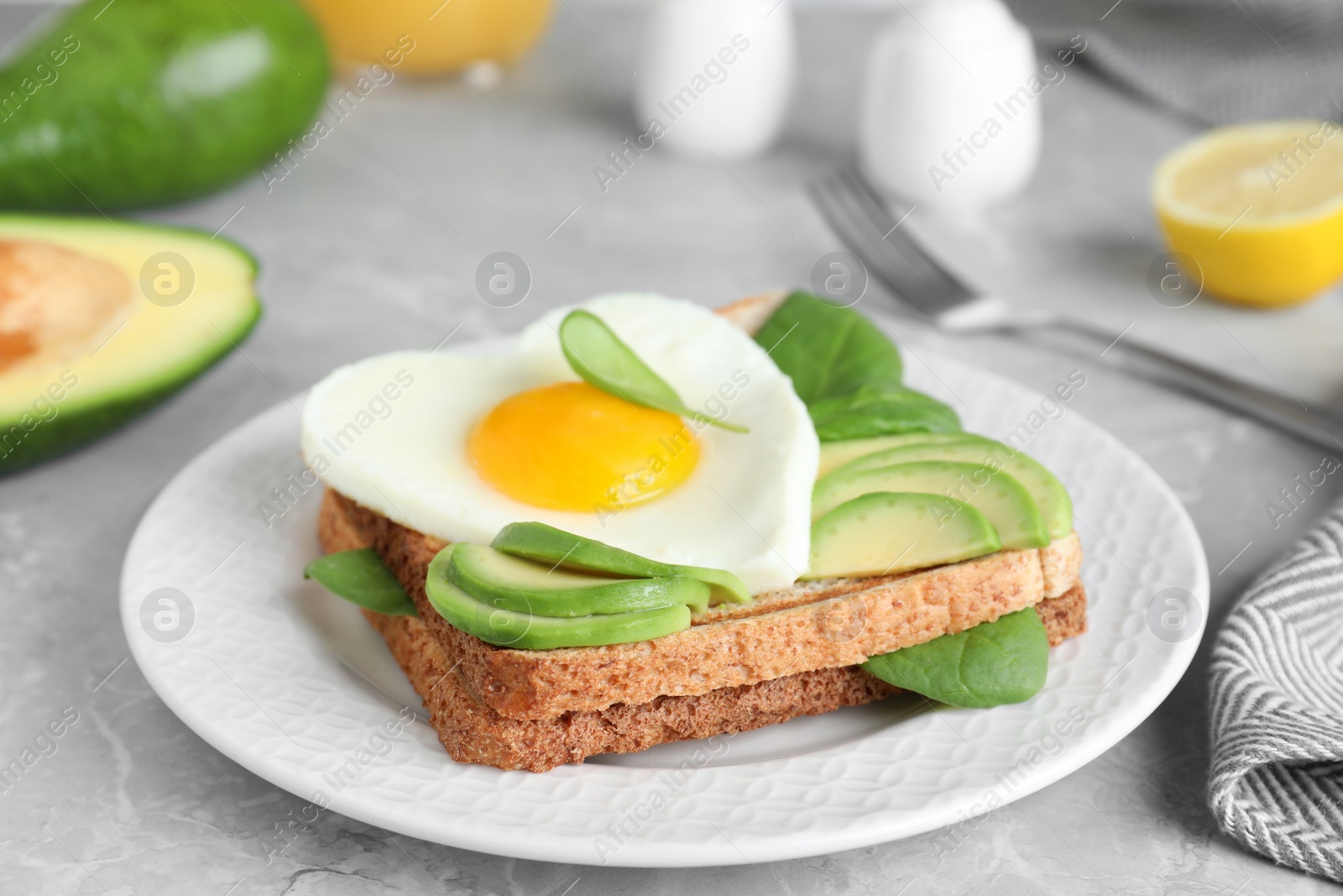 Photo of Tasty breakfast with heart shaped fried egg served on  grey table