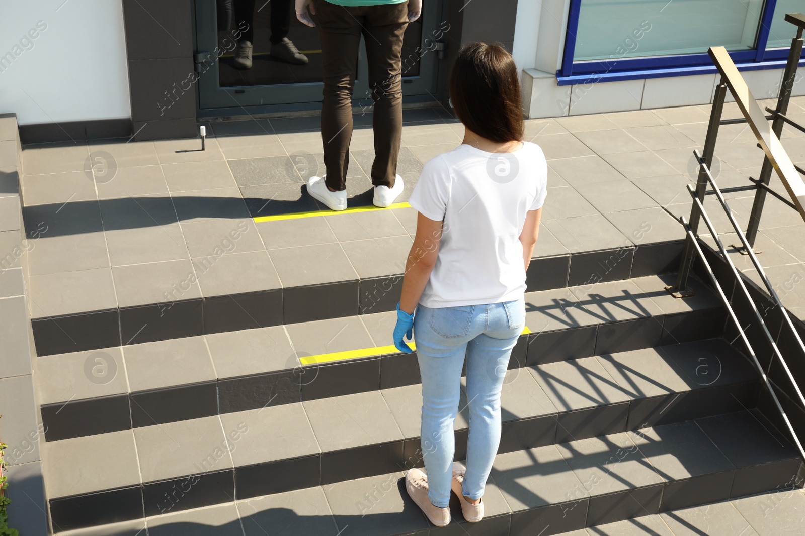 Photo of People keeping social distance in line on stairs outdoors. Coronavirus pandemic