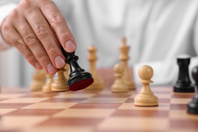 Man moving chess pieces at checkerboard, closeup