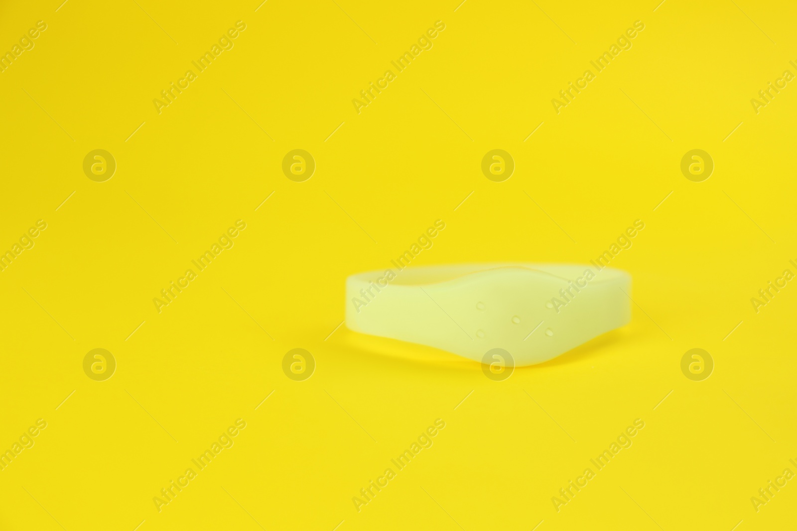 Photo of Insect repellent wrist band on yellow background