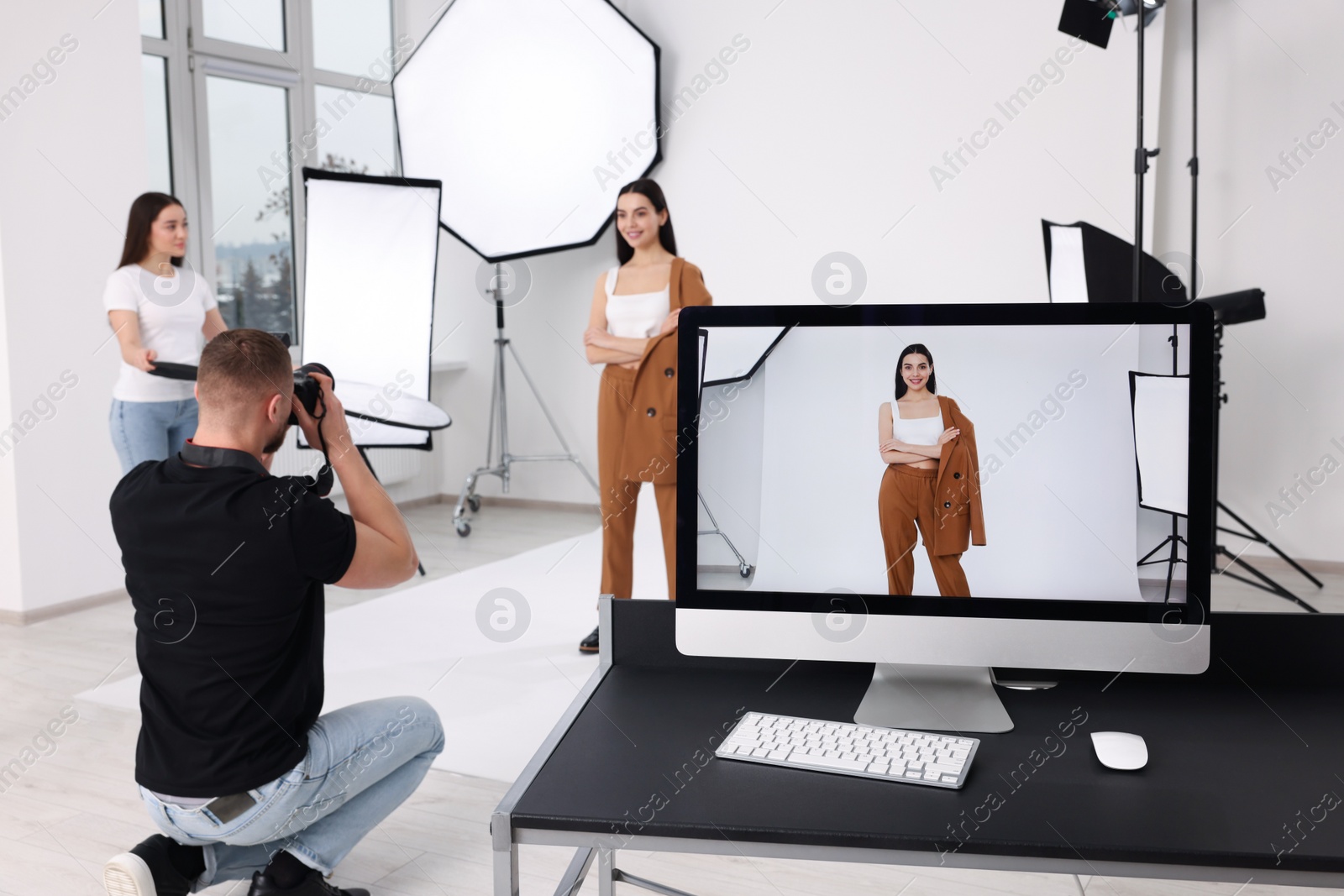 Photo of Professional photographer and assistant working with beautiful model in modern photo studio, selective focus