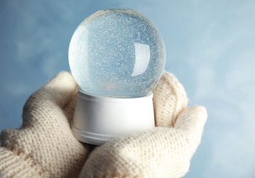 Photo of Woman holding empty snow globe on color background, closeup