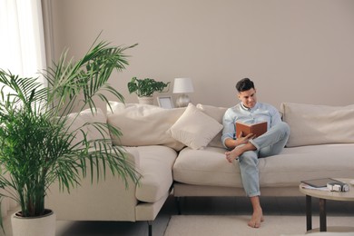 Photo of Man reading book on sofa in living room