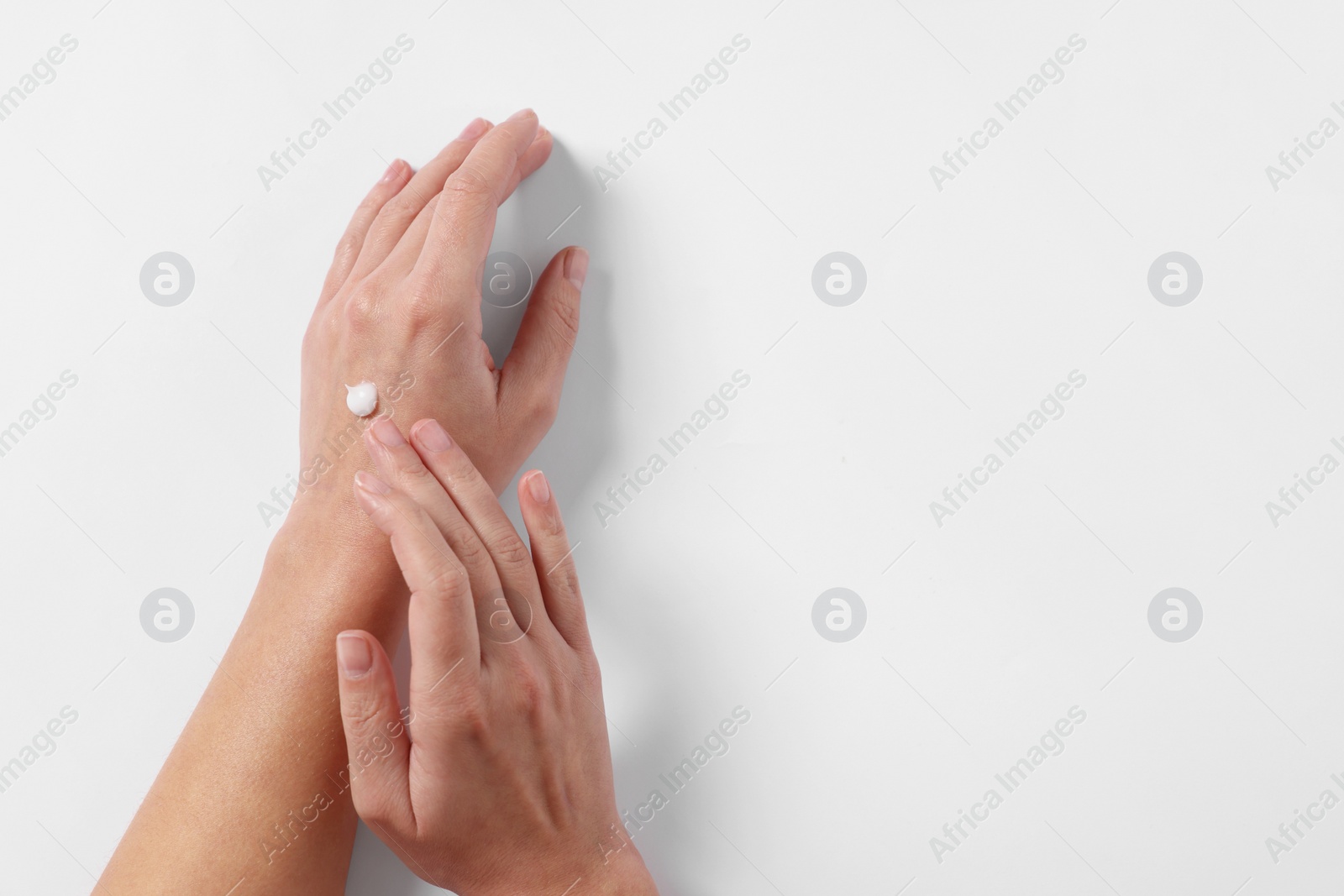 Photo of Woman with cosmetic cream on hand against white background, top view. Space for text