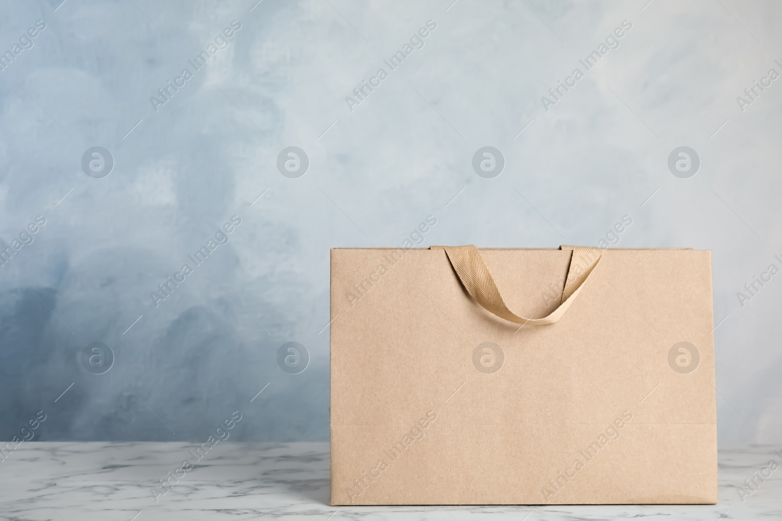 Photo of Paper shopping bag on table against color background. Mock up for design