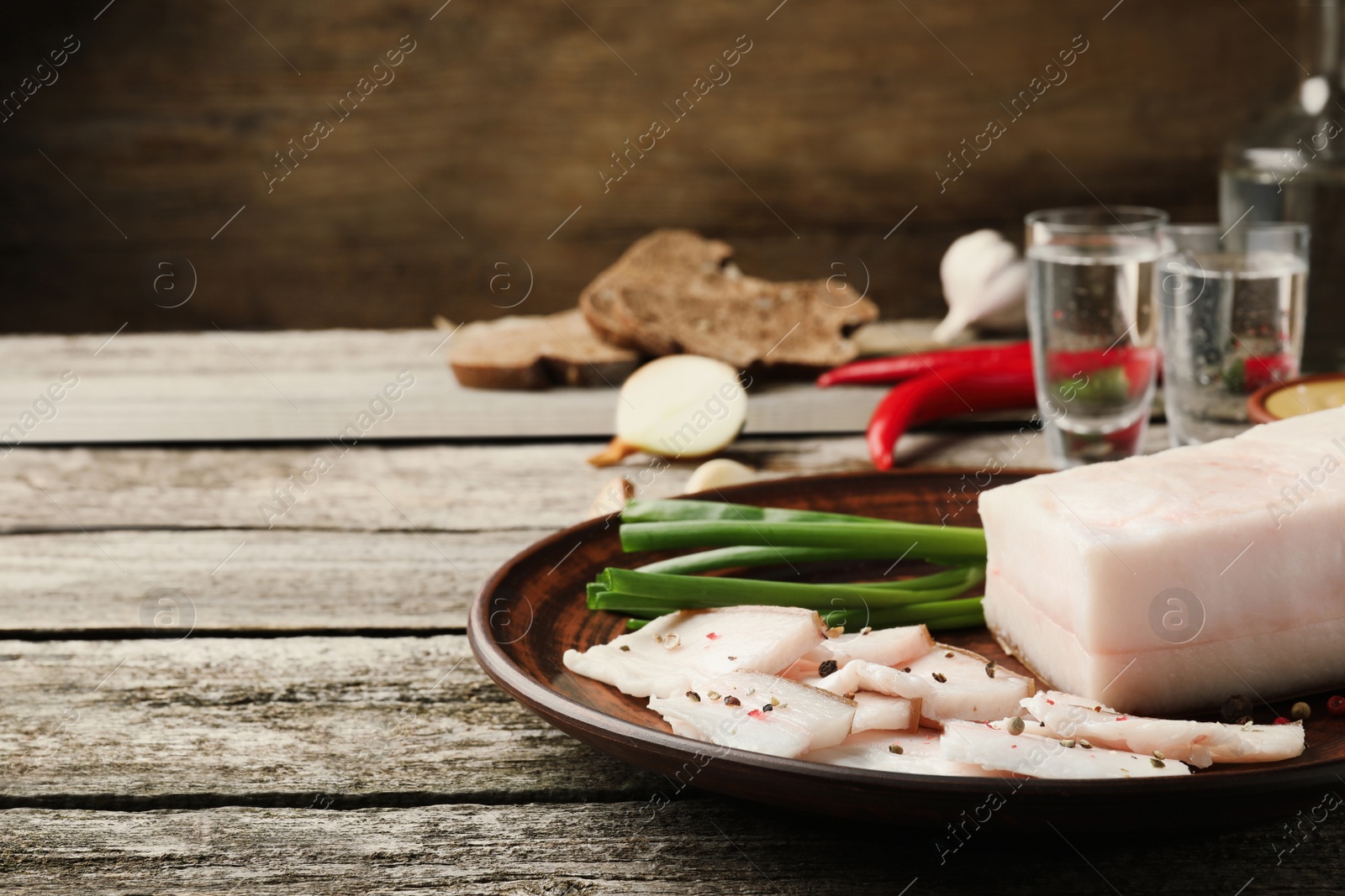 Photo of Tasty salt pork with green onion served on wooden table, space for text