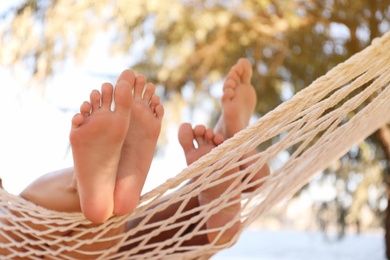 Photo of Couple relaxing in hammock on beach, closeup. Summer vacation