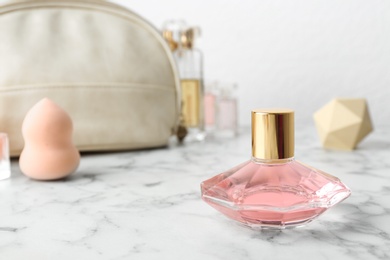 Photo of Bottle of perfume and cosmetics on marble table. Space for text