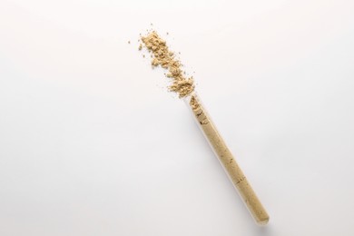 Photo of Glass tube with ginger powder on white background, top view